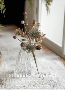 Décoration de Noël avec feuilles dorées et pommes de pin dans un vase sur fond de neige