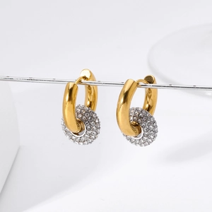 Dettaglio di cerchi dorati con ciondoli in argento pavé su sfondo bianco pulito