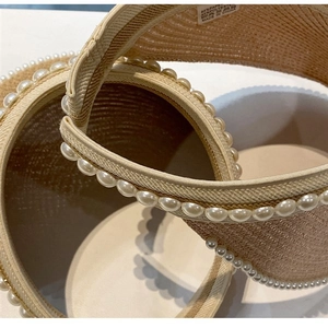 Detail of elegant straw sun visor with pearl trim and high-quality woven paper texture