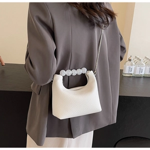Close-up of white pebble grain mini bag featuring pearl bead handle and chain strap