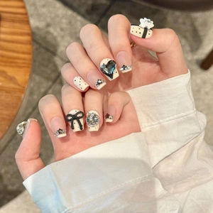 Handmade press-on nails with bow designs, heart rhinestones, and French black tips