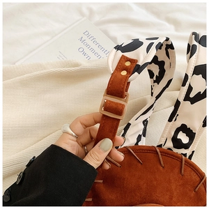 Close-up of cow print strap and brown suede backpack with adjustable buckle detail