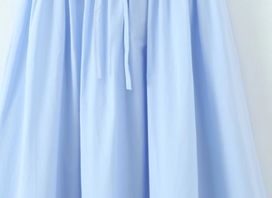 Détail de la robe en coton bleu clair avec cordon à la taille et texture tissée