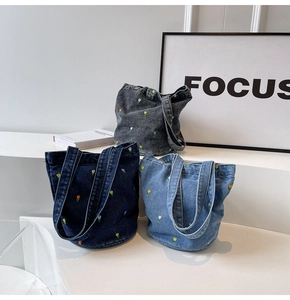Detailansicht der Denim-Beuteltaschen mit Blumenstickerei in Blau- und Grautönen