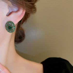 Close-up of vintage emerald oval stud earrings with green rhinestones on model