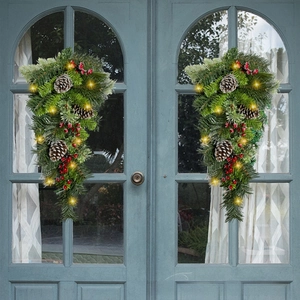 Symmetric Christmas teardrop swags with pine cones and LED lights on a double door