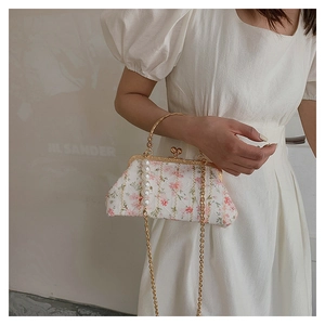 Detail of floral embroidery and pearl accents on a shell-shaped chain crossbody bag