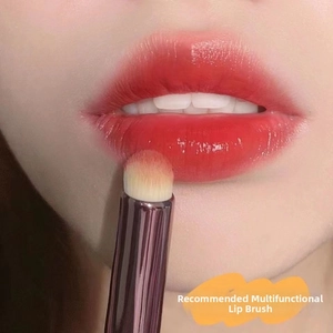 Detailed view of a round silicone lip brush blending lipstick on a model's lips