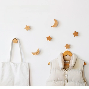 Star and moon wood wall hooks shown holding bags and hats on a white wall