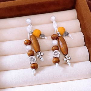 Close-up of bohemian earrings with wooden beads, faux pearls, and cross charms on velvet