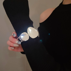 Macro view of a large silver irregular double-layer cuff bracelet on a black sleeve