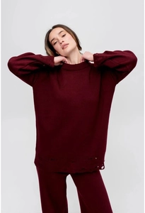 Close-up of distressed knit cuffs and hem on a solid wine red crewneck sweater set