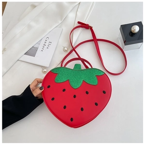 Close-up detail of a strawberry shaped crossbody bag with red gloss finish and green leaf top