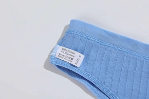 Close-up of wash label on blue cotton underwear showing 95% cotton fabric and size S