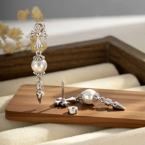 Silver cross earring with pearl and rivet cone pendant, front and back view on wood tray