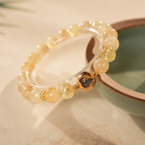 Macro shot of citrine beaded bracelet with golden hollow heart charm and diamond accents