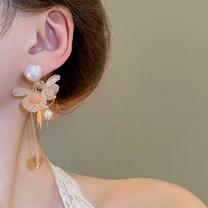 Dettaglio di orecchini lunghi a nappa con fiori e perle indossati da una modella