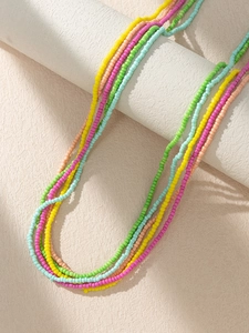 Close-up of vibrant multi-layered Bohemian seed bead body chains on a white pedestal