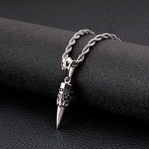 Detailed shot of silver bullet pendant with skull embossing and twisted chain necklace