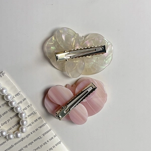 Close-up of elegant floral acetate hair clips in pink and iridescent white on white