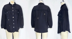 Detailed view of black denim jacket showing distressed holes, frayed hem, and chest pockets