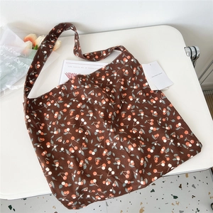 Detail of a brown corduroy tote bag featuring a cherry pattern and soft shoulder strap