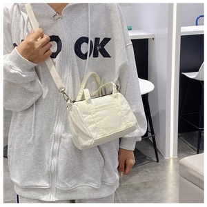 Close-up of cream corduroy boston bag worn crossbody by a model in a cafe setting