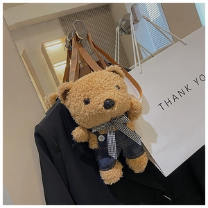 Detail of plush brown teddy bear crossbody bag featuring a denim jumpsuit and plaid bow tie