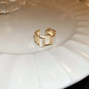 Detail view of the gold oval zircon ring featuring white inlay and layered metal texture