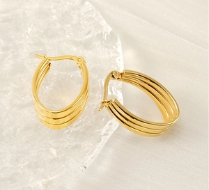 Macro view of gold stainless steel oval hoop earrings with triple ribbed texture