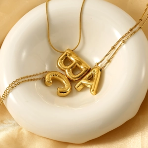 Detail of gold puffed balloon initial pendants A B C on polished snake chain necklace