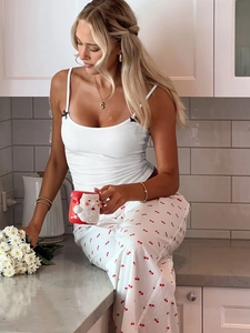 Détail du caraco blanc avec nœud noir et pantalon de pyjama à imprimé cerises
