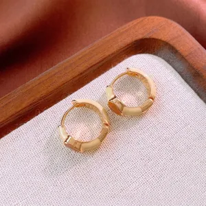 Vintage gold bamboo hoop earrings with cream enamel finish displayed on jewelry tray