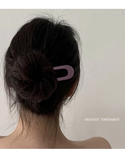 Rear view of model wearing a matte purple U-shaped hair pin in a stylish bun updo