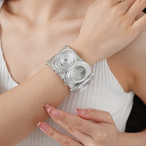 Macro shot of silver multilayered wrap bangle with spiral details on a female wrist