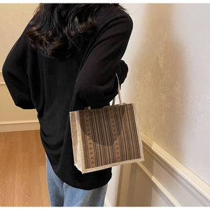 Detailed back view of model holding a brown striped linen tote bag for daily commute