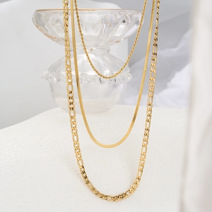 Detailed view of triple-layered golden Cuban and snake bone chain necklace set