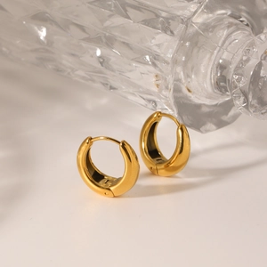 Polished 18K gold U-shaped thick hoop earrings on a minimalist white surface