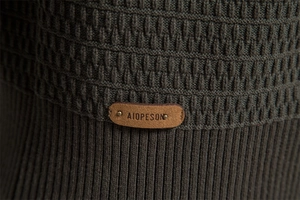 Close-up of dark green knit texture and premium leather brand tag on men's cardigan
