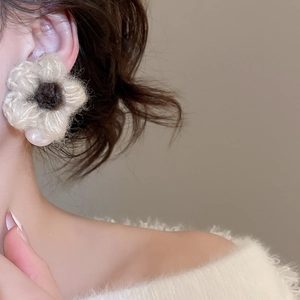 Detailed close-up of handmade knit flower earrings with soft wool texture and pearl drop