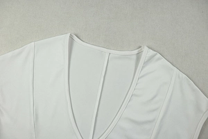 Detailed close-up of the V-neckline and fabric texture of the white bodycon dress