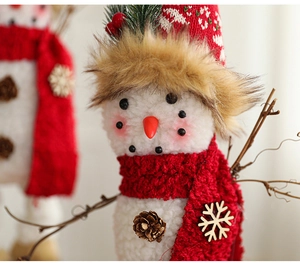 Close-up of plush Christmas snowman with red knit hat, scarf and wooden branch arms