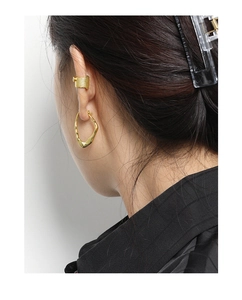 Close-up of a gold wave earring and textured ear cuff on a female model with sleek styling