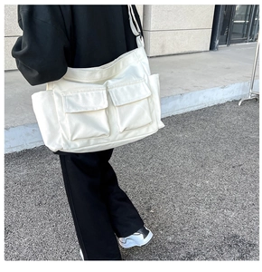 Detail view of white canvas crossbody bag featuring two large functional front flap pockets