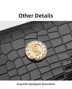 Close-up of golden rhinestone S-logo hardware on black crocodile pattern bag detail
