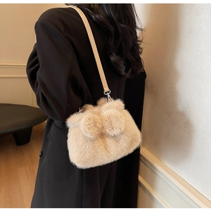 Detail of beige plush bucket bag with soft faux fur texture and slim leather shoulder strap