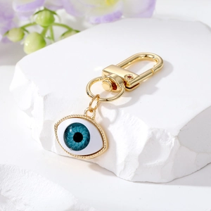 Blue resin evil eye charm with gold alloy ring on white stone and purple flowers