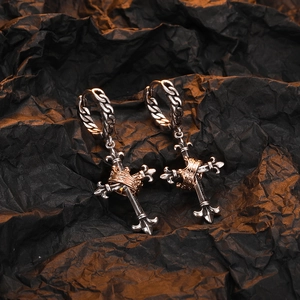 Detail of vintage Thai silver cross earrings featuring a golden crown on a dark background