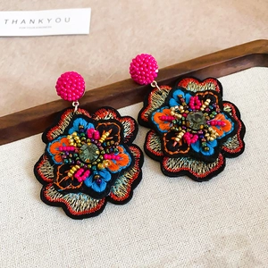 Macro detail of bohemian embroidered floral earrings with colorful beads and gemstones