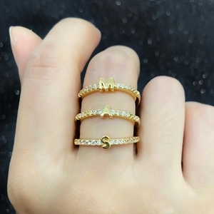 Adjustable gold plated letter rings M, A, S with cubic zirconia insets on female hand